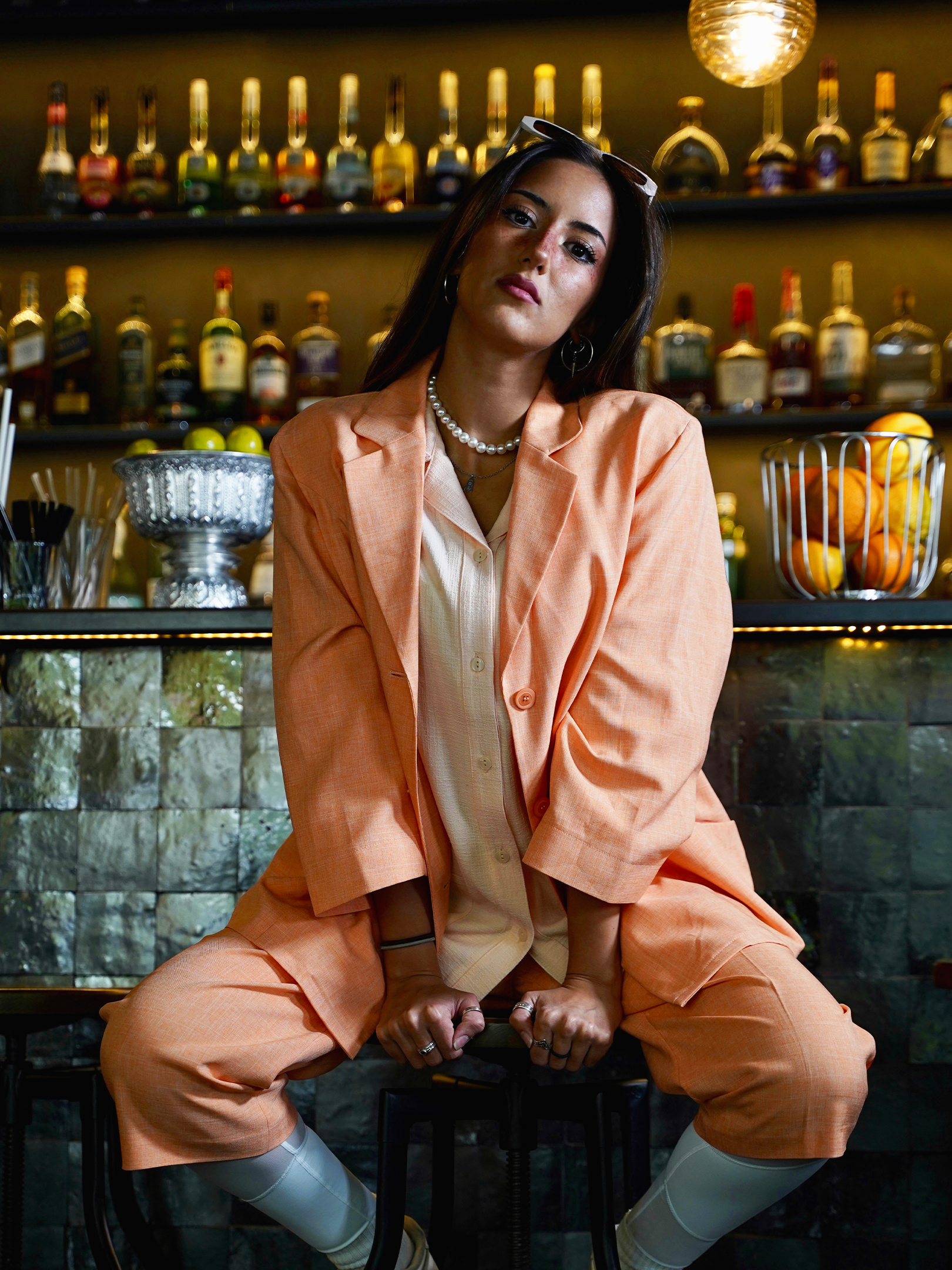 Model sitzt in VIDAFO Cotton Blazer Peach auf einem Barhocker